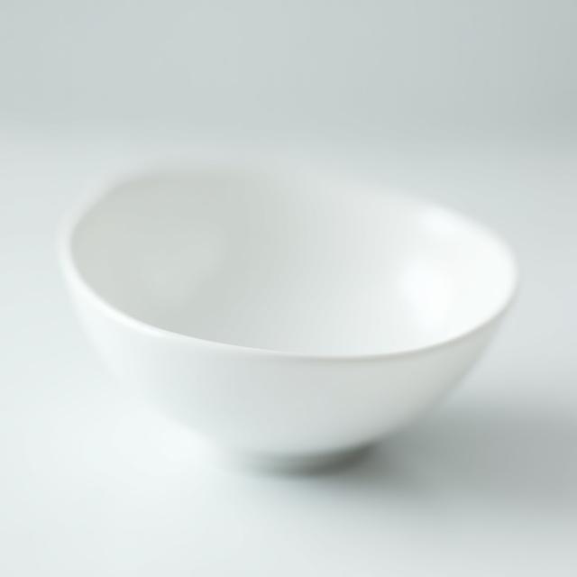 En tynn, nesten gjennomsiktig hvit porselensskål med en matt, silkemyk overflate som reflekterer lyset diskret.